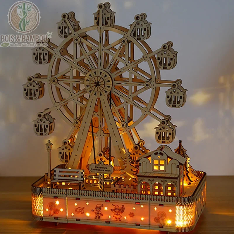 Grande roue en bois. Une maquette lumineuse détaillée d'une fête foraine avec une grande roue et des maisonnettes, réalisée en bois découpé et diffusant une lumière chaude tamisée.