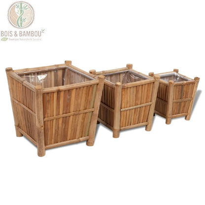 Jardinières en Bambou. Un ensemble de trois bacs à fleurs carrés de tailles différentes, fabriqués en tiges de bambou naturel avec une doublure intérieure protectrice, sur fond blanc.
