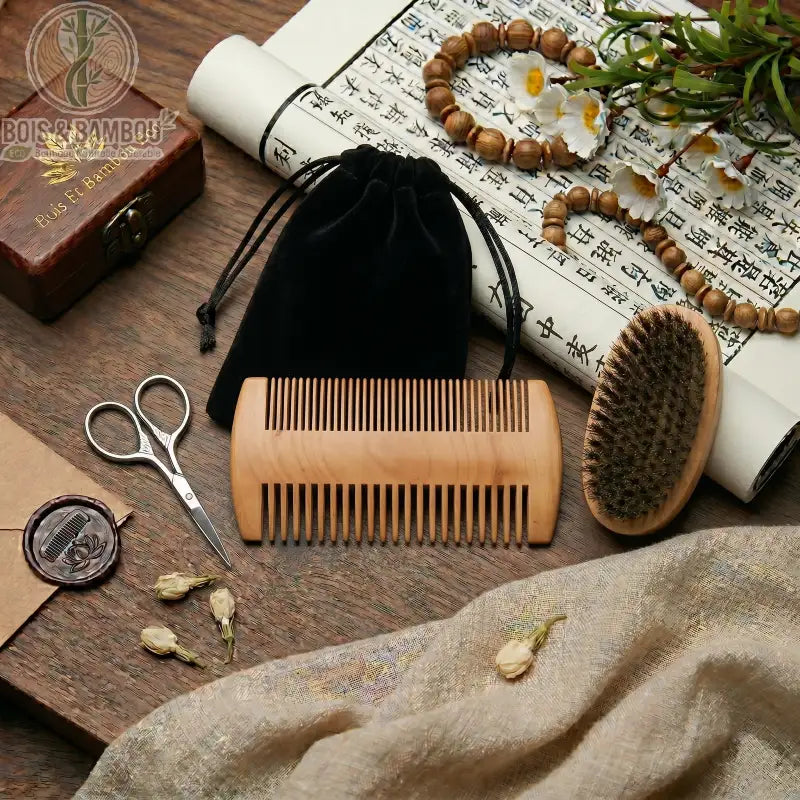 Kit d'entretien barbe professionnelle comprenant un peigne double en bois, une brosse en poils de sanglier, des ciseaux de précision et un pochon en velours sur une table en bois.
