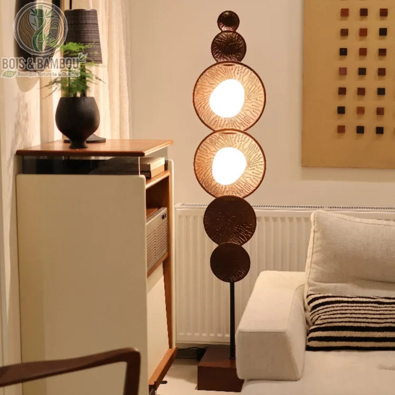 Lampadaire en bois massif , un luminaire sur pied au design sculptural composé de disques superposés et de deux globes lumineux intégrés, apportant une touche artistique et chaleureuse à un coin de salon.