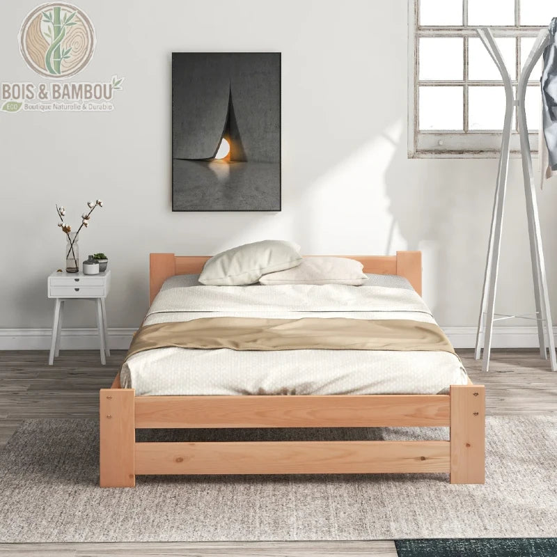 Lit Futon en Bois Massif. Un cadre de lit bas en bois clair au design minimaliste, doté d'une petite tête de lit, placé sur un tapis gris dans une chambre lumineuse et moderne.