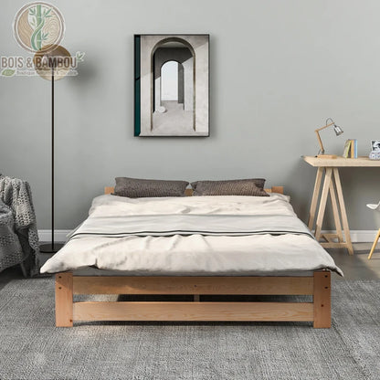 Lit Tatami en Bois de Pin 2. Un lit bas minimaliste en bois clair avec couette blanche, disposé sur un tapis gris dans une chambre moderne avec un bureau et un cadre mural d'arcade.