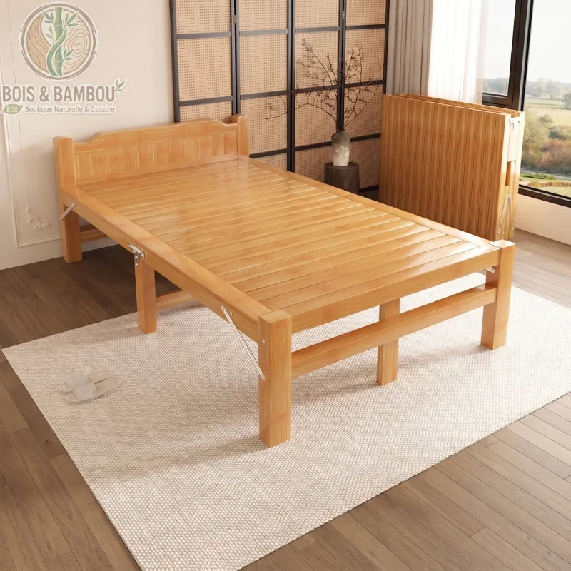 Lit en Bambou Massif Classique 100x200x35. Lit une place large et long en bambou massif verni, présenté ouvert sur un tapis blanc et replié en arrière-plan pour illustrer sa fonction gain de place.