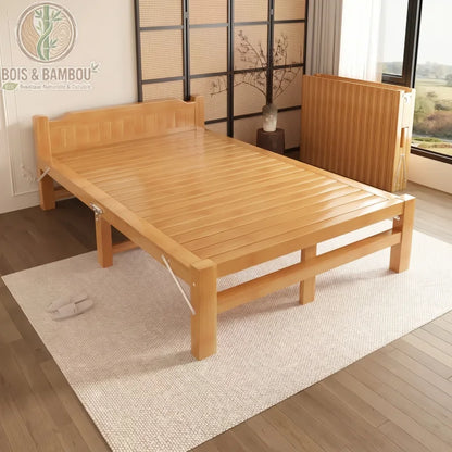 Lit en Bambou Massif Classique 120x190x35. Grand lit pliant en bambou massif verni installé dans une pièce lumineuse, accompagné d'un second exemplaire replié pour illustrer le gain de place optimal.