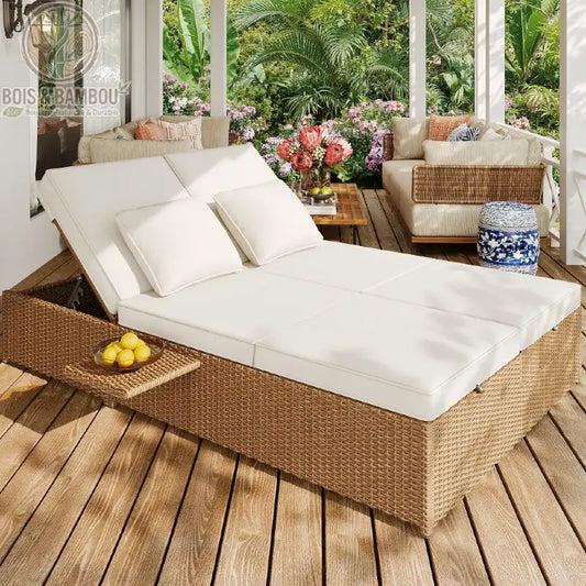 Lit de Jardin Double en Rotin. Un grand lit d'extérieur en résine tressée avec matelas et coussins blancs, dossiers inclinables et tablette latérale sur une terrasse en bois.