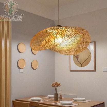 Lustre en bambou tressé au design organique et aérien. Sa structure en maille fine diffuse une lumière tamisée et chaleureuse, créant des jeux d'ombres délicats sur les murs. Cette suspension artisanale apporte une touche d'élégance naturelle et de sérénité à une salle à manger ou un salon contemporain.