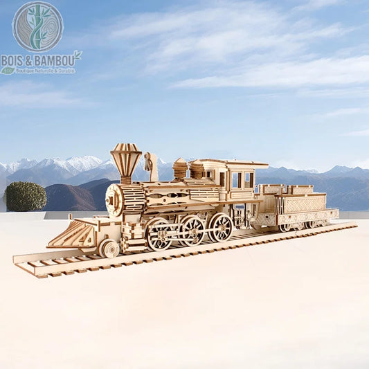Maquette de Train à vapeur Sakura Station. Une réplique détaillée d'une locomotive à vapeur avec son tender sur des rails, réalisée en bois découpé devant un paysage de montagnes.