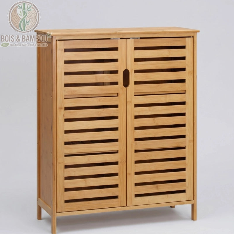 Meuble bas de salle de bain en bambou neutre. Une armoire de rangement compacte en bambou naturel avec des portes à lattes horizontales et une poignée centrale découpée, présentée sur un fond gris.
