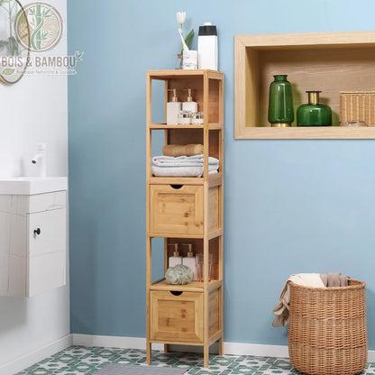 Meuble de salle de bain en bambou. Une étagère colonne étroite en bois clair avec deux tiroirs et trois niches de rangement, installée dans une salle de bain aux murs bleus.