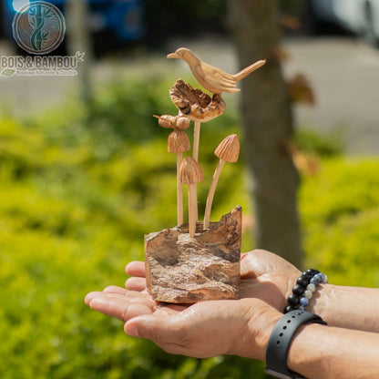 Sculpture oiseau bois sur champignons tenue dans deux mains en extérieur