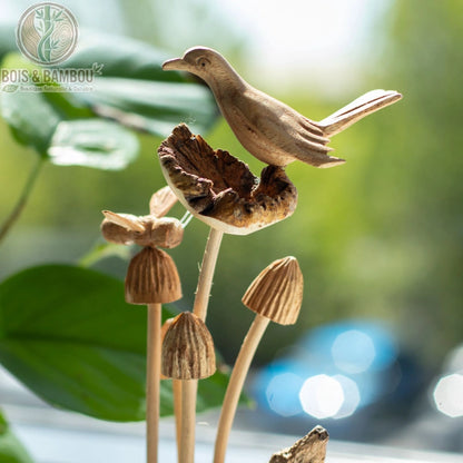 Gros plan d'une sculpture oiseau bois posée parmi des champignons sculptés