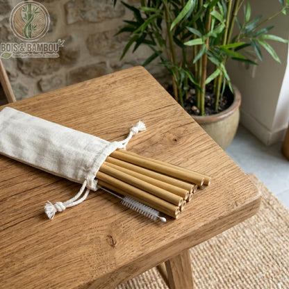 Pailles en Bambou Bio Ensemble 6 Pailles Naturelles avec Pochette – lot de 6 pailles bambou jaune naturel avec pochon coton blanc sur plateau bois, plante bambou en arrière-plan.