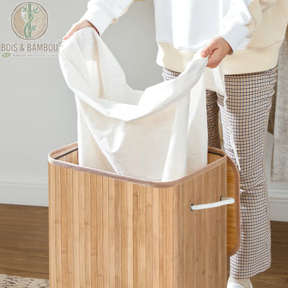 Panier a Linge Bambou Naturel avec Couvercle 72L situation 2. Une personne retire le sac en tissu blanc amovible d'un panier à linge en lattes de bambou naturel doté de poignées en corde blanche.