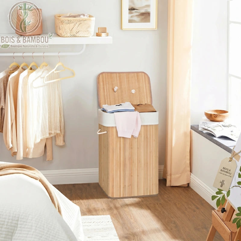 Panier à Linge en Bambou Claire rectangulaire avec couvercle ouvert, rempli de vêtements. Structure en lattes de bambou clair avec doublure en tissu blanc.