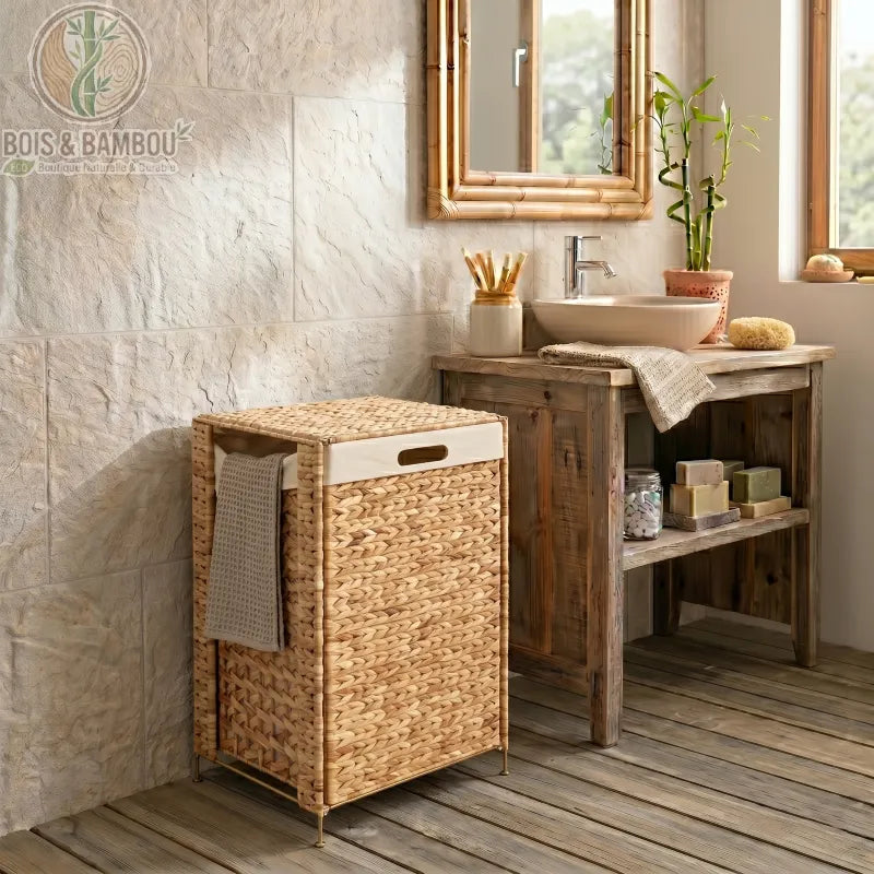 Panier a Linge en Noyer Massif modele2. Panier à linge rectangulaire en jacinthe d'eau tressée avec sac amovible blanc, élégamment placé dans une salle de bain rustique à côté d'un meuble sous vasque.