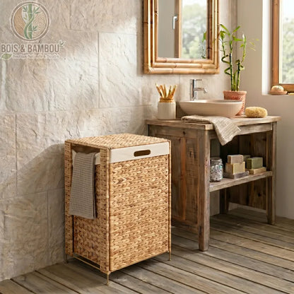 Panier a Linge en Noyer Massif modele2. Panier à linge rectangulaire en jacinthe d'eau tressée avec sac amovible blanc, élégamment placé dans une salle de bain rustique à côté d'un meuble sous vasque.