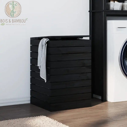 Panier a Linge en Pin Massif noir 44 44 66 cm. Coffre à linge design en bois de pin noir avec structure à claire-voie et couvercle, installé dans une buanderie moderne à côté d'un lave-linge.