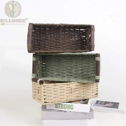 Panier de rangement en corde tressée. Trois paniers rectangulaires en corde tressée de couleurs marron, vert et beige, empilés sur des livres sur un fond blanc. Rangement bohème.