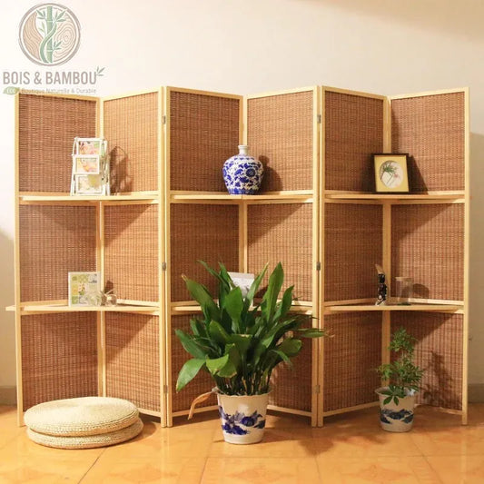 Paravent à six panneaux pliants en bois clair et tissage dense de bambou, offrant un fond chaleureux et texturé. Modèle polyvalent avec étagères intégrées sur deux niveaux pour exposer des plantes, vases ou cadres, structurant l'espace avec élégance.