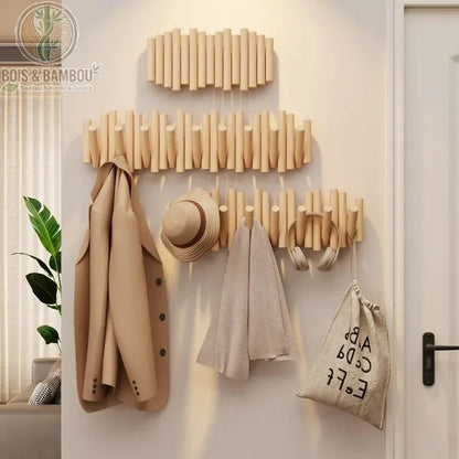 Patère Piano en Bois Massif. Trois supports muraux artistiques en bois clair avec crochets rabattables, chargés d'un manteau, d'un chapeau et d'accessoires dans une entrée.
