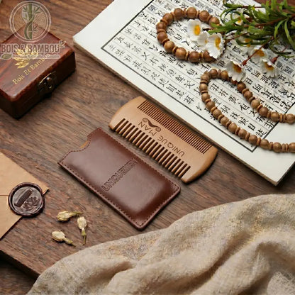 Peigne à barbe en bois avec étui en cuir marron. Peigne double face gravé Unique Man sur une table en bois avec décor zen, calligraphie et perles. Accessoire de soin pour homme.