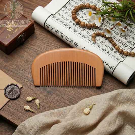 Peigne de Poche en Bois Naturel demi-lune, dents larges. Sur table en bois avec rouleau calligraphie, perles, fleurs blanches, tissus, cachet de cire. Accessoire beauté bio.