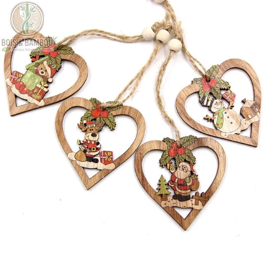 Pendentifs Cœur de Noël, un ensemble de quatre ornements en bois en forme de cœur ajouré. Chaque pièce illustre un personnage festif coloré — un ours, un renne, un Père Noël et un bonhomme de neige — décoré de houx et suspendu par une ficelle de jute ornée d'une perle en bois.