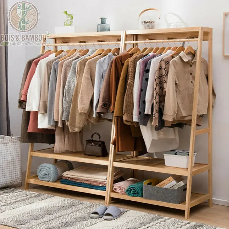 Penderie Bambou Naturel avec etageres et Crochets double. Deux portants en bois clair alignés, chargés de vêtements sur cintres, avec des étagères bas de rangement organisées sur un tapis gris.