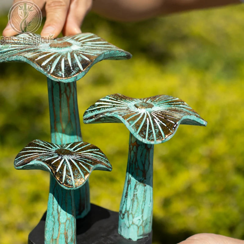 Champignon en bois décoratif finition vert patiné tenu à la main, gros plan sur les chapeaux striés