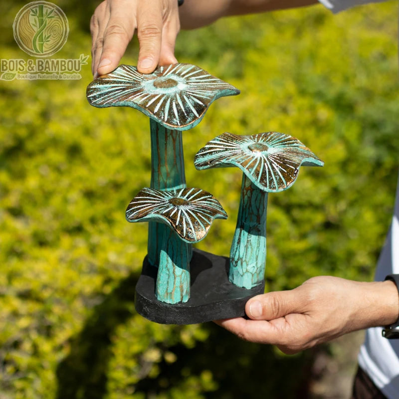 Champignon en bois décoratif vert patiné sur socle noir présenté à la main en extérieur