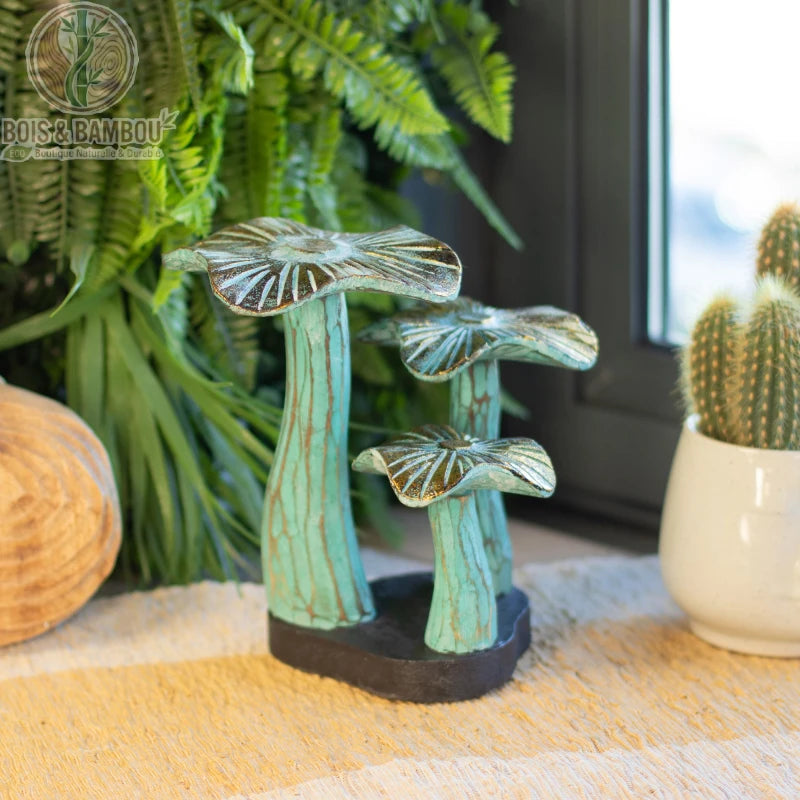 Champignon en bois décoratif vert patiné posé sur une table près de plantes vertes