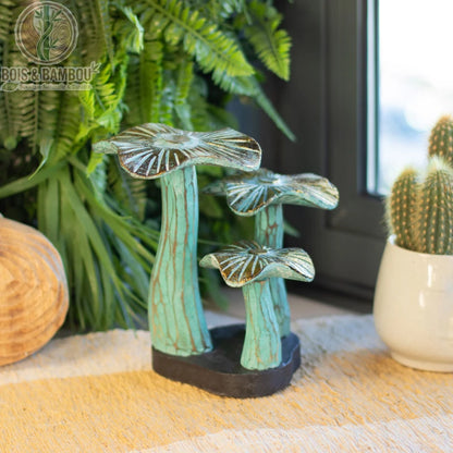 Champignon en bois décoratif vert patiné posé sur une table près de plantes vertes