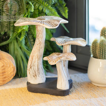 Champignon en bois décoratif blanc patiné sur socle noir posé près de plantes d'intérieur