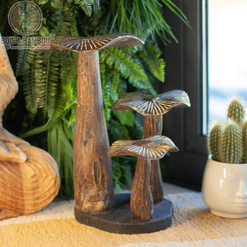 Champignon en bois décoratif bois naturel sur socle posé sur une table près de plantes vertes
