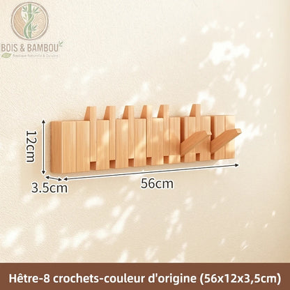 Porte Manteau Piano hetre claire 8 crochets. Un porte-manteau mural de 56 cm en bois de hêtre naturel avec 8 crochets rabattables, affichant ses dimensions précises sur un mur ensoleillé.