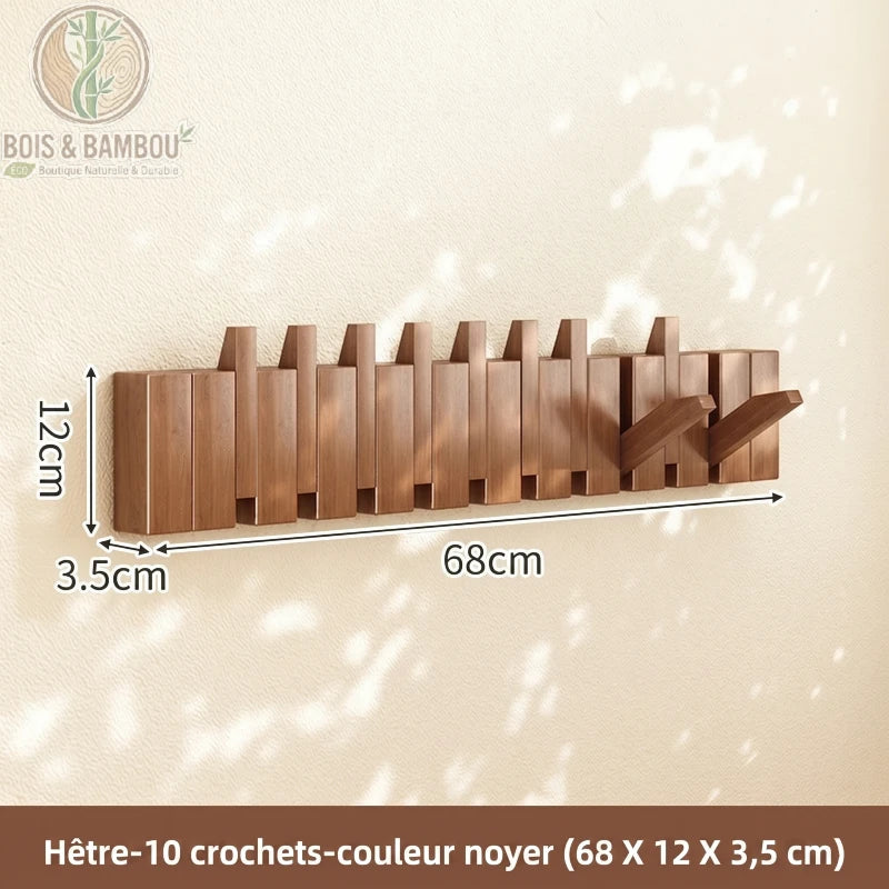 Porte Manteau Piano hetre fonce 10 crochets. Un porte-manteau mural de 68 cm en bois de hêtre couleur noyer avec 10 crochets rabattables, affichant ses dimensions sur un mur ensoleillé.