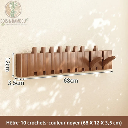 Porte Manteau Piano hetre fonce 10 crochets. Un porte-manteau mural de 68 cm en bois de hêtre couleur noyer avec 10 crochets rabattables, affichant ses dimensions sur un mur ensoleillé.