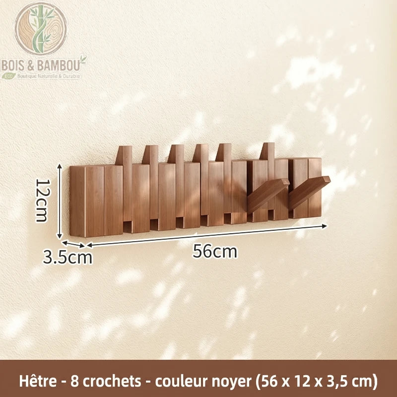 Porte Manteau Piano hetre fonce 8 crochets. Un porte-manteau mural de 56 cm en bois de hêtre couleur noyer avec 8 crochets rabattables, affichant ses dimensions sur un mur ensoleillé.