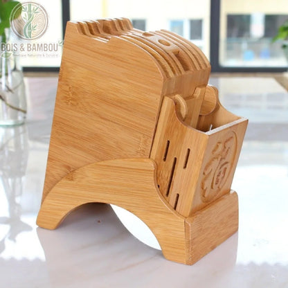 Porte-couteau de cuisine en bambou. Un bloc de rangement robuste en bambou avec plusieurs fentes pour couteaux et un compartiment gravé, posé sur un plan de travail blanc.