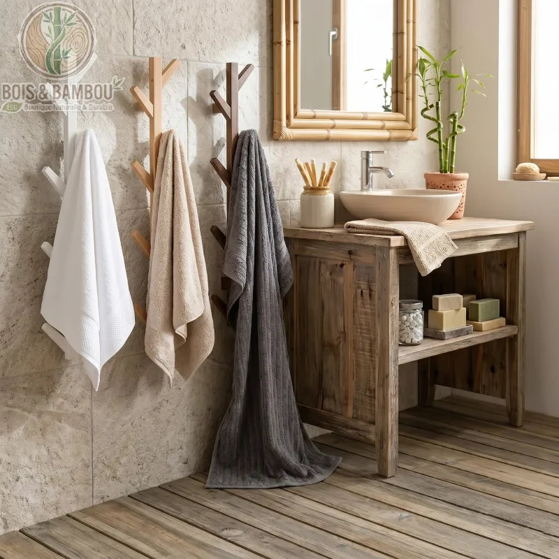 Porte-manteau mural en bambou en forme d'arbre, en trois finitions (blanc, bois clair, bois foncé), suspendu avec des serviettes dans une salle de bain rustique.