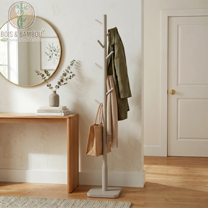 Porte manteau sur pieds en bois d hevea beige. Porte-manteau sur pied beige au design minimaliste avec plusieurs branches, portant des vêtements et un sac dans une entrée moderne et lumineuse.