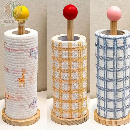 Porte-serviettes en bois minimaliste. Trois supports verticaux en bois avec des boules colorées (jaune, rouge, rose) présentant différents rouleaux de papier essuie-tout décorés.