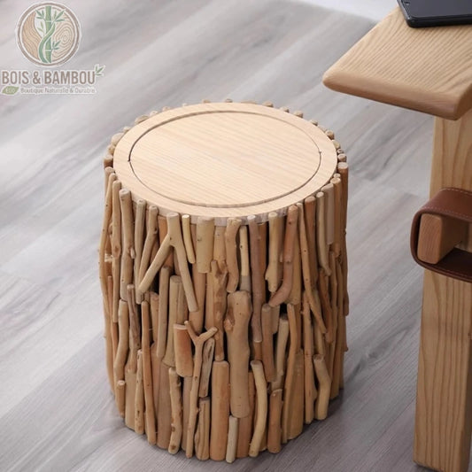 Poubelle design en bois naturel situation. Poubelle décorative en forme de souche, habillée de branches de bois flotté assemblées, posée sur un parquet près d'un bureau moderne en bois clair.