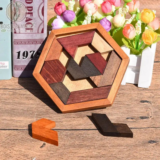 Puzzle mosaïque polygone en bois. Un casse-tête hexagonal contenant des pièces géométriques en bois de différentes teintes, posé sur une table en bois près de fleurs décoratives.