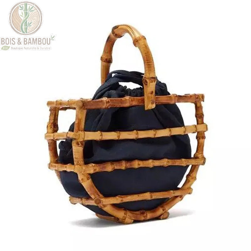 Sac corbeille en bambou a pompon details 2. Gros plan sur un sac artisanal en tiges de bambou courbées avec poignée rigide, contenant un pochon en tissu noir amovible, présenté sur un fond blanc.