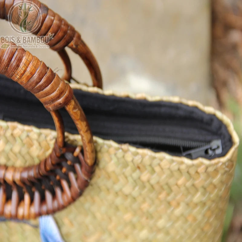 Sac main retro en bambou tisse details. Gros plan sur la fermeture éclair noire et les anses rondes en bambou sculpté d'un sac à main artisanal en paille tressée, soulignant les finitions soignées.