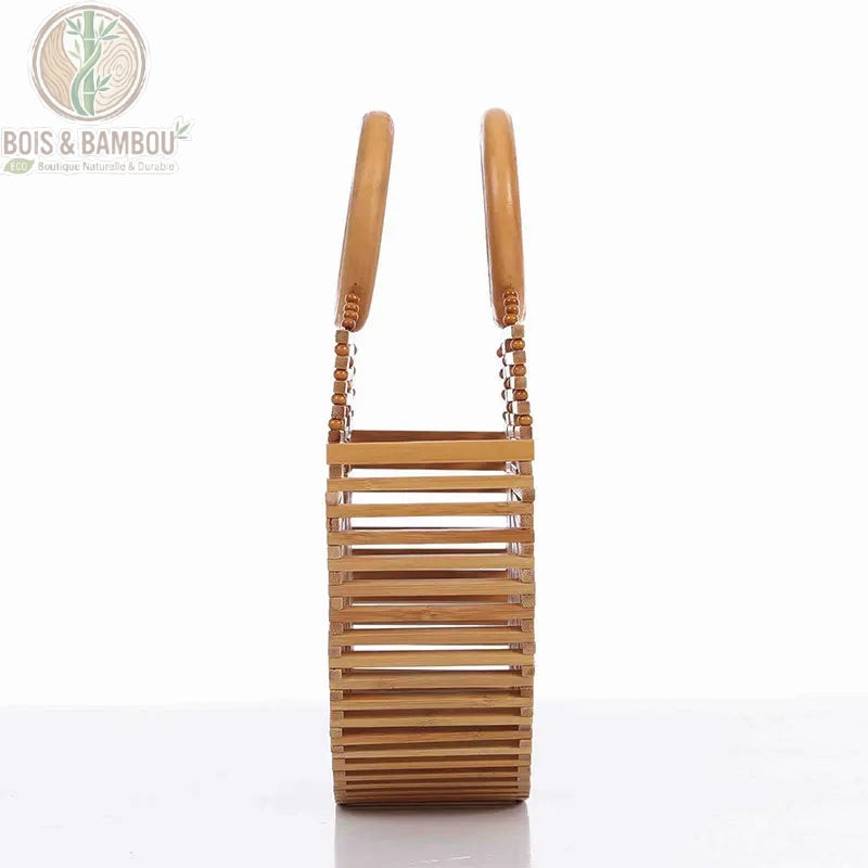 Sac panier Demi Lune en bambou situation 3. Vue latérale d'un sac à main artisanal en bambou montrant sa structure en lattes horizontales et ses deux grandes anses circulaires sur un fond blanc épuré.