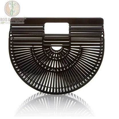 Sac panier en bambou tresse noir 1. Vue de face d'un sac à main demi-lune en bambou noir intense avec finition brillante, présentant un design ajouré géométrique sur un fond blanc avec reflet.