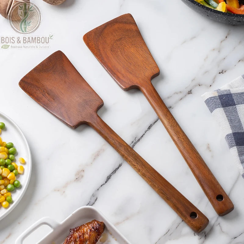 Spatule bois anti-brulure 34 cm posee sur plan de travail marbre avec assiettes en arriere plan, Bois et Bambou Eco