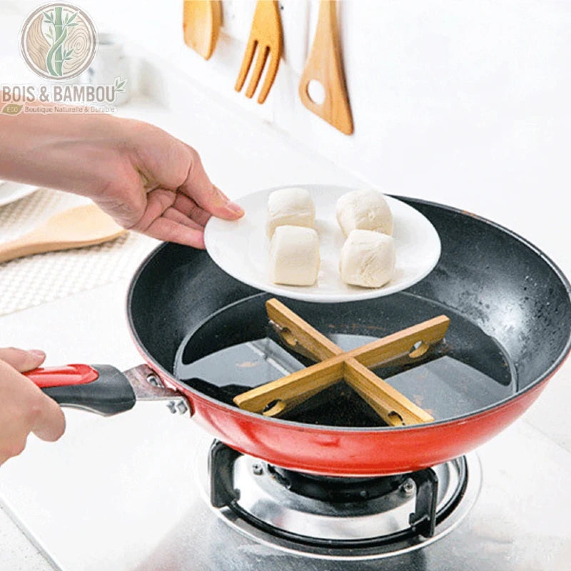 Support de Pot Croisé en Bambou Amovible Dessous de Plat Casserole – main plaçant une poêle sur le support croisé bambou, démonstration usage multifonctionnel cuisine.